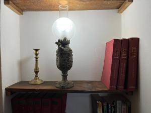 une lampe assise sur une étagère avec des livres dans l'établissement L'Antico Palazzo - Mansion With Pool, à Toano