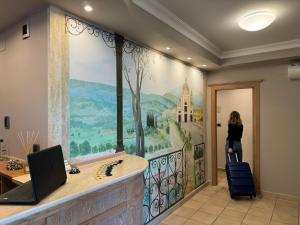 a woman standing in front of a wall with a painting at Hotel Cladan in Assisi