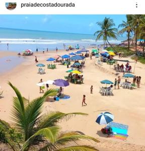 ein Strand mit Sonnenschirmen und Menschen am Strand in der Unterkunft Casas lindas no paraiso! in Costa Dourada