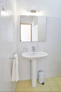 a white bathroom with a sink and a mirror at University View Loft in Coimbra