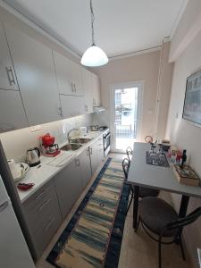 kuchnia z białymi szafkami i stołem z krzesłami w obiekcie Patras Stay w mieście Patras