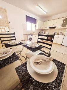 una cocina con 3 sillas y una mesa con platos y cubiertos. en Delightful Poolside apartment, en Pafos
