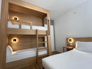 een slaapkamer met 2 stapelbedden met witte lakens bij YUGOGO MAZZINI 41 Trento Centro in Trento