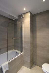 a bathroom with a shower and a tub and a toilet at Ealing Broadway by Viridian Apartments in Ealing