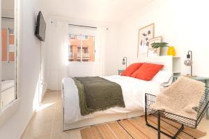 een witte slaapkamer met een bed en een stoel bij Apartamento coqueto con terraza junto a Candelaria in Candelaria