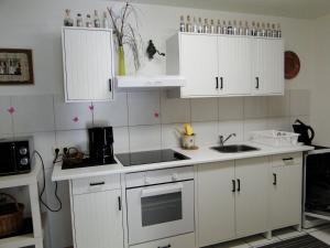 a kitchen with white cabinets and a sink at Ferienwohnung Hotte´s Hütte in Ettenheim +16 photos