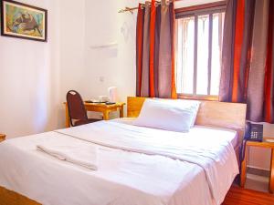 a bedroom with a white bed with a window at Explorers Hub in Kampala
