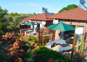 patio ze stołami i parasolami przed budynkiem w obiekcie Crocodile Pools Resort w mieście Gaborone