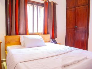 a bed with a wooden headboard and a window at Explorers Hub in Kampala