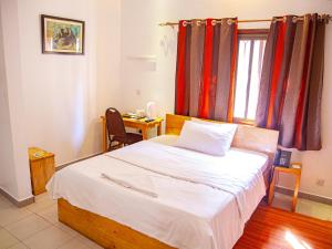 a bedroom with a bed and a desk and a window at Explorers Hub in Kampala