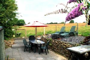 a patio with a table and chairs and an umbrella at Bryn-y-Gof Llangrannog in Blaencelyn