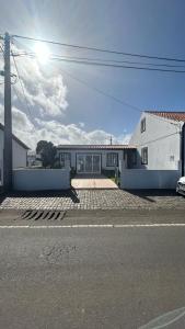 una casa blanca con un estacionamiento delante de ella en Hortênsia's AL, en Praia da Vitória