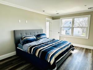 a bedroom with a bed with a striped comforter and a window at Belmar NJ 5 Min Walk to Beach, Sleeps 16+ in Belmar