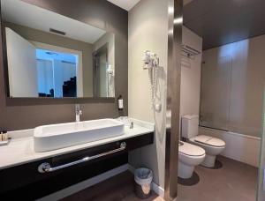 ein Badezimmer mit Waschbecken, Toilette und Spiegel in der Unterkunft HG La Molina in La Molina