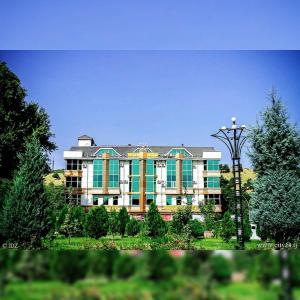 ORIYO DUSHANBE HOTEL في دوسهانبي: مبنى كبير شبابيكه خضراء واضاءة الشارع
