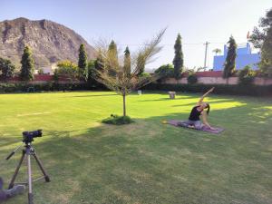 a woman doing yoga in a field next to a tree at Pari Resort with Nature View in Pushkar