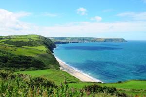 uma vista para a praia e para o oceano numa colina em 2 Castle Hall Llangrannog em Llangranog