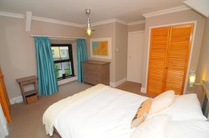 a bedroom with a large white bed and a dresser at 2 Castle Hall Llangrannog in Llangranog