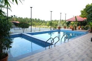a swimming pool with two chairs in the middle at GREEN MOUNT RESORTS in Malaiyāndipattanam +88 photos