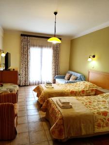 um quarto de hotel com três camas e uma janela em Philoxenia Hotel em Paranesti