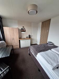 1 dormitorio con 1 cama grande y cocina en B&B Marijke, en De Koog