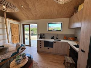 a kitchen with a stove and a couch in a room at Petite Perfection tiny house at Lake Hawea in Lake Hawea