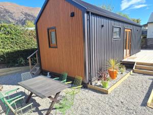 a tiny house with a picnic table and chairs at Petite Perfection tiny house at Lake Hawea in Lake Hawea