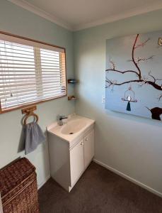 ein Badezimmer mit einem Waschbecken und einem Baumgemälde an der Wand in der Unterkunft Character on Capell large house perfect for extended family in Lake Hawea
