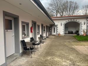 uma fila de cadeiras e uma mesa fora de um edifício em Pension Donau em Hanôver