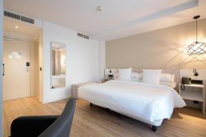 a white bedroom with a large bed and a chair at Óbal Urban Hotel in Marbella