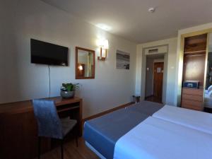 a hotel room with a bed and a desk and a television at Hotel Saylu in Granada