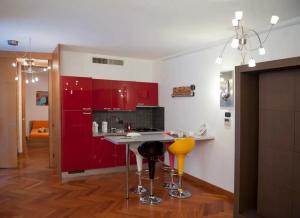 een keuken met rode kasten en gele barkrukken bij Tricolore - Sottocorno Charme Loft in Milaan
