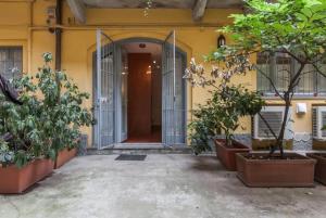 een ingang naar een geel huis met bomen en planten bij Tricolore - Sottocorno Charme Loft in Milaan