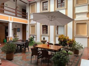 un patio con mesas, sillas y una sombrilla en Hotel el regidor, en Buga