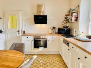 a kitchen with white cabinets and a table and a microwave at Appartements BERGTRAUM in Gröbming