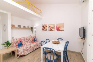 a living room with a table and chairs and a couch at Le Dimore Ibiscus in Stintino