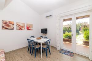 a dining room with a table and chairs and a tv at Le Dimore Ibiscus in Stintino