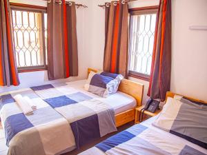 two beds in a room with two windows at Explorers Hub in Kampala