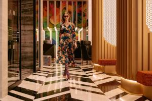 a woman in a dress walking down a hallway at NYX Esperia Palace Hotel Athens by Leonardo Hotels in Athens