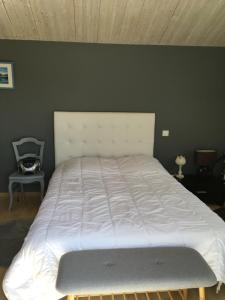 duże białe łóżko w sypialni ze ścianą w obiekcie Chambre grise w mieście Barbâtre