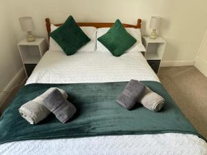 1 cama con 2 almohadas y manta verde en Scotch Terrace - 3 Bed House, en Whitehaven