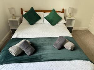 a bed with two pillows and a green blanket at Scotch Terrace - 3 Bedrooms - Sleeps 6 in Whitehaven