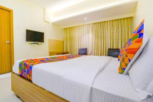 a bedroom with a large bed and a tv at FabExpress Kuber in Navi Mumbai