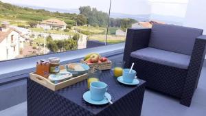 een tafel met een dienblad met ontbijtproducten op een balkon bij Apartamentos Marina Cordelia in O Grove