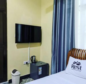 a bedroom with a bed and a tv on the wall at Rest Inn Lounge & Lodge in Dar es Salaam