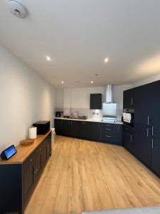 een grote keuken met zwarte kasten en een houten vloer bij Private ensuite room near London in Dagenham