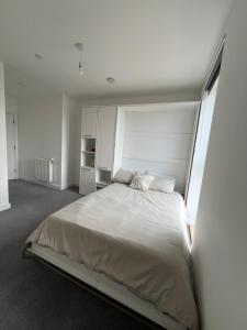 a bedroom with a large bed in a white room at Private ensuite room near London in Dagenham