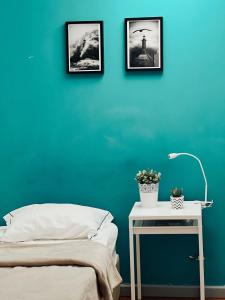 1 dormitorio con pared azul, cama y mesa en By Doors Hostel, en Oporto