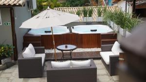 a patio with two hot tubs and a table with an umbrella at Pousada Juannas Buzios in Búzios