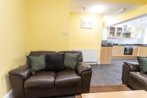 a living room with a leather couch and a kitchen at April Disc - Long Stay - Contractors in Bristol
